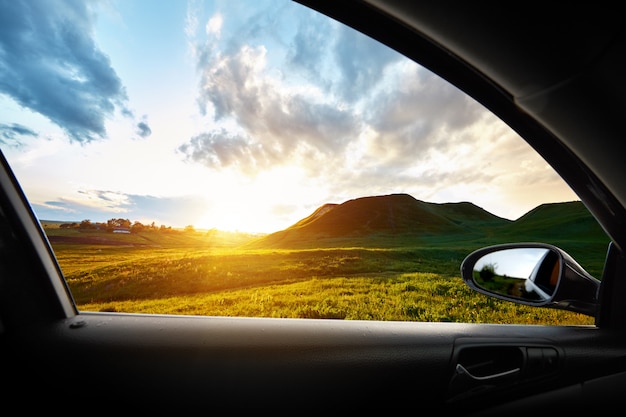 Colline verte au coucher du soleil de l'intérieur d'une voiture