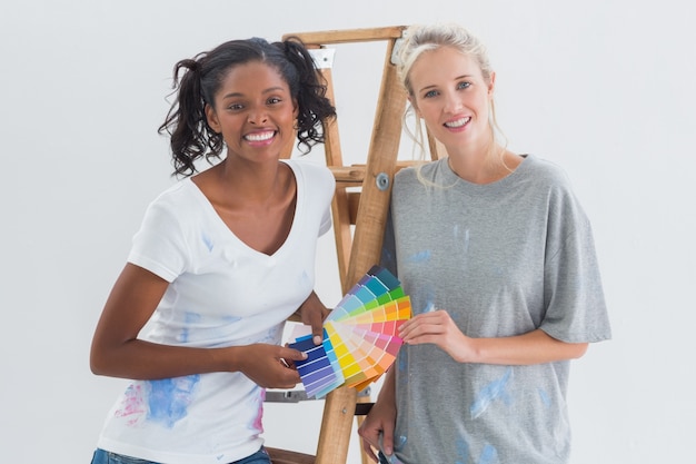 Colocataires amicales choisissant la couleur pour le mur regardant la caméra