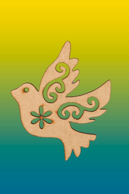 Photo colombe en bois suspendue avec des motifs de noël sur fond festonné de couleur.