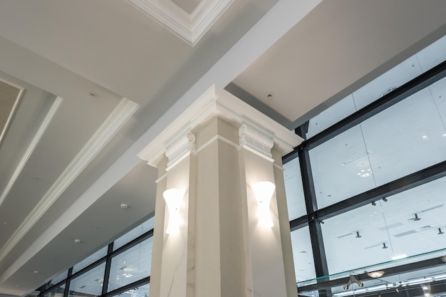 Colonne à l'intérieur avec plafond suspendu et grillagé avec spots halogènes et construction de cloisons sèches dans une pièce vide du magasin ou de la maison Plafond tendu blanc et de forme complexe