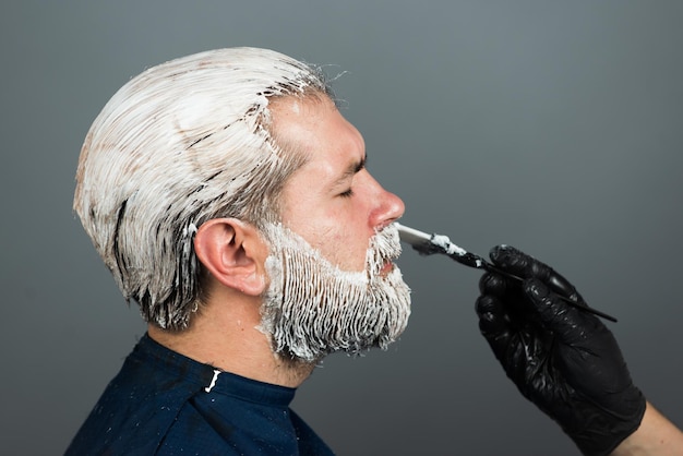 Coloration des cheveux homme barbu. Coloration de la barbe. Le coiffeur fait une coupe de cheveux colorée.