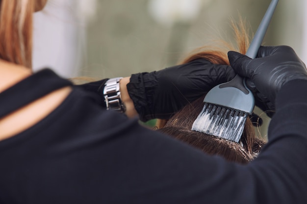 Coloration des cheveux de jeune beau client d'un coiffeur professionnel dans un gros plan de salon de beauté