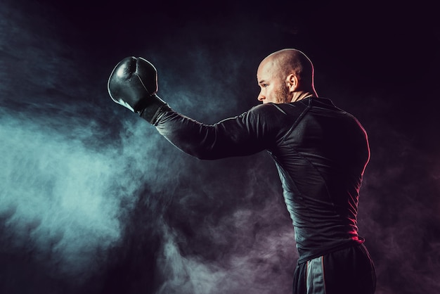 Combats de boxeur sportif, frappant uppercut sur un espace noir avec de la fumée