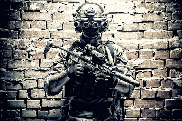 Photo combattant de groupe tactique des forces spéciales de l'armée dans la mission cqb utilisant un casque radio regardant à travers un dispositif d'imagerie thermique à vision nocturne à quatre lentilles sur une petite mitraillette armée d'un casque avec silencieux