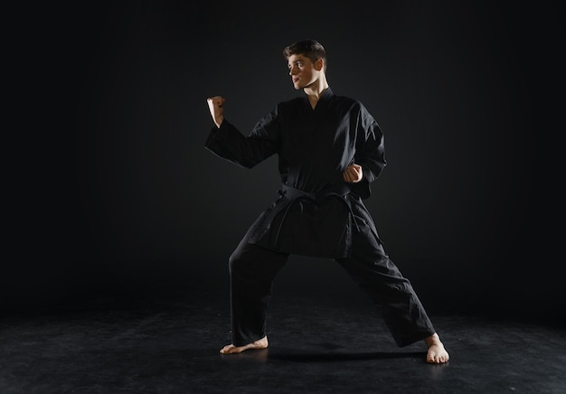 Combattant de karaté masculin en kimono noir, position de combat. Homme en séance d'entraînement, arts martiaux