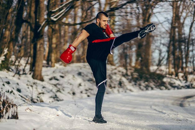 Combattant musclé fort avec des gants de boxe sparring dans la nature au jour d'hiver enneigé