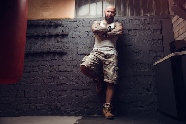 Combattant tatoué brutal en fight club avec sac de boxe