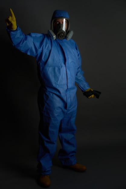 Photo combinaison chimique anti-radioactive avec gants de masque à gaz sur fond gris et détecteur dramatique