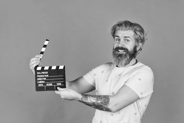 Comédie ou drame Regarder un film Réalisateur Casting d'acteur Scène de tournage Série préférée Production cinématographique Producteur créatif Un homme barbu tient un battant de film Cinéaste Clapperboard copy space