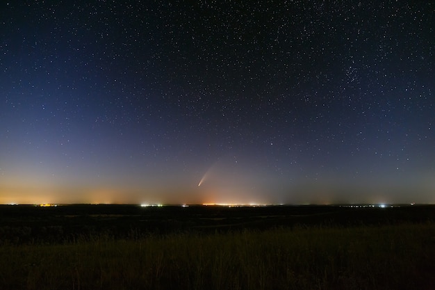 Comète lumineuse NEOWISE dans le ciel étoilé. Objet de l'espace lointain au-dessus de l'horizon.