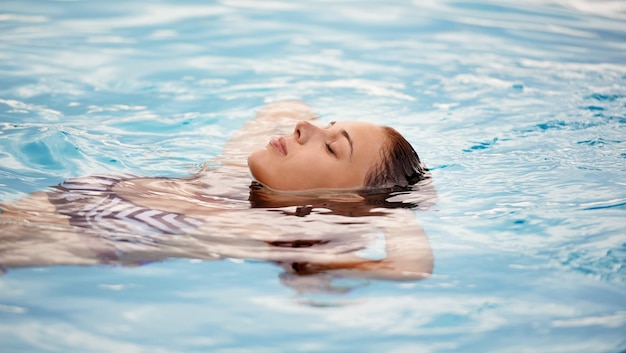 Comme flotter sur un nuage Photo recadrée d'une belle jeune femme se relaxant dans une piscine