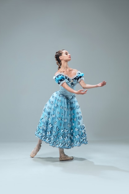 Comme une poupée. Belle danseuse de salon contemporaine isolée sur fond gris studio. Artiste professionnelle sensuelle dansant la valse, le tango, le slowfox et le quickstep. Flexible et sans poids.