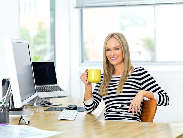 Commencez votre journée avec du java Photo d'une belle jeune femme travaillant à son bureau tout en sirotant un verre