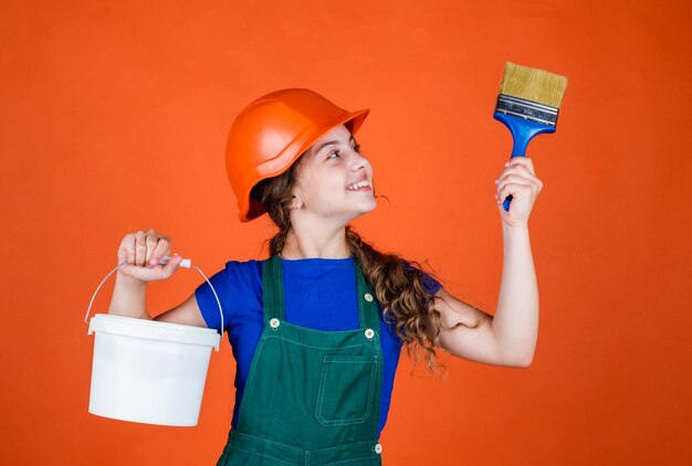 Commençons le concept de l'enfance et des personnes adolescente prête pour la peinture fille dans un casque de protection avec un pinceau développement de la garde d'enfants fille dans un casque de protection tient le pinceau