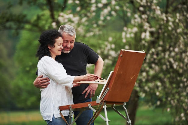 Comment ça vous regarde. Couple d'âge mûr ont des journées de loisirs et travaillent ensemble sur la peinture dans le parc