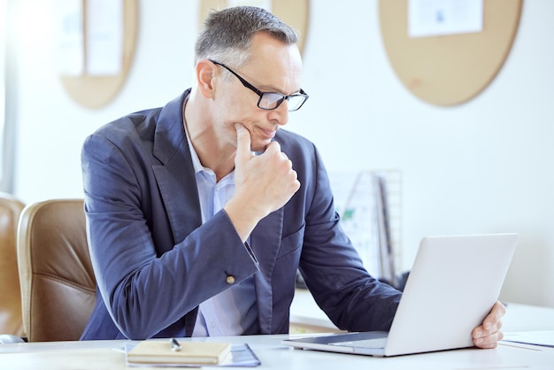 Comment puis-je améliorer cette photo d'un homme d'affaires mature utilisant un ordinateur portable dans un bureau au travail