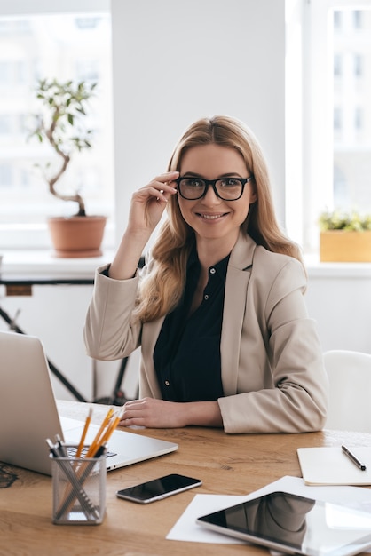 Comment puis-je vous aider? belle jeune femme en vêtements décontractés intelligents ajustant ses lunettes