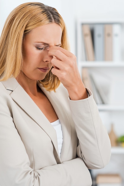 Comment vais-je passer cette journée ? Femme d'affaires mûre déprimée touchant son nez