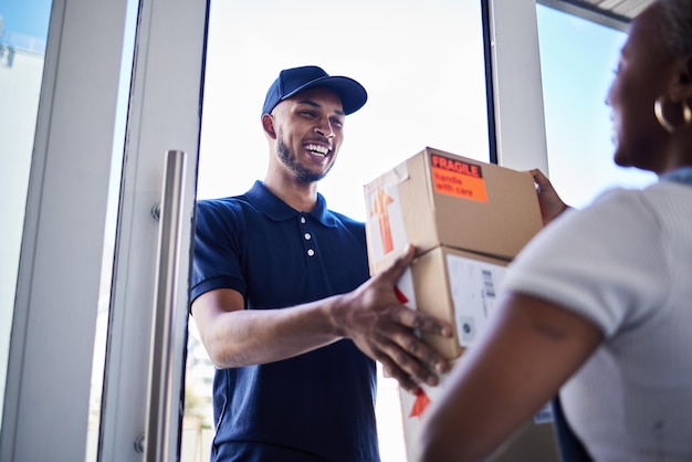 Commerce électronique livreur heureux homme avec boîte et femme à sa porte d'entrée achat en ligne ou chaîne d'approvisionnement logistique ou distribution et femme africaine reçoit son colis en carton avec un sourire