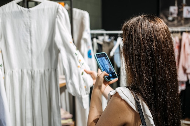 Photo commerce électronique et vente en ligne femme prenant une photo de vêtements dans la boutique de vente d'occasion utilisée