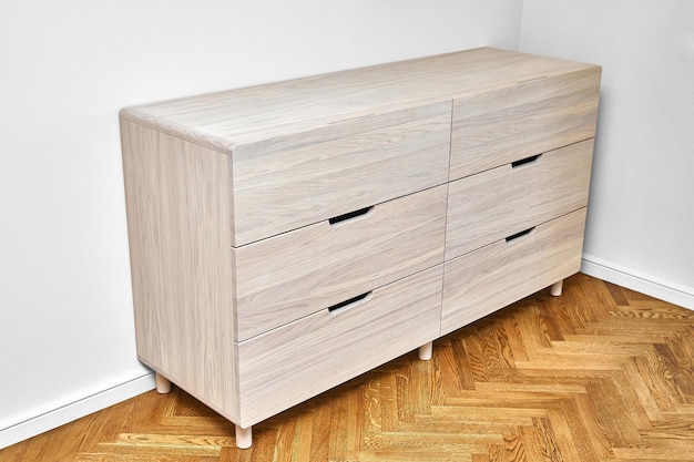 Commode en bois de chêne massif blanchi avec tiroirs à tirette repose sur parquet