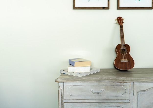 Commode vintage avec un ukulélé et quelques livres