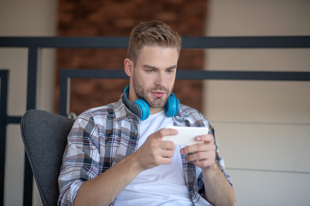 Communication en ligne. Un jeune homme tapant un message à l'aide de son smartphone