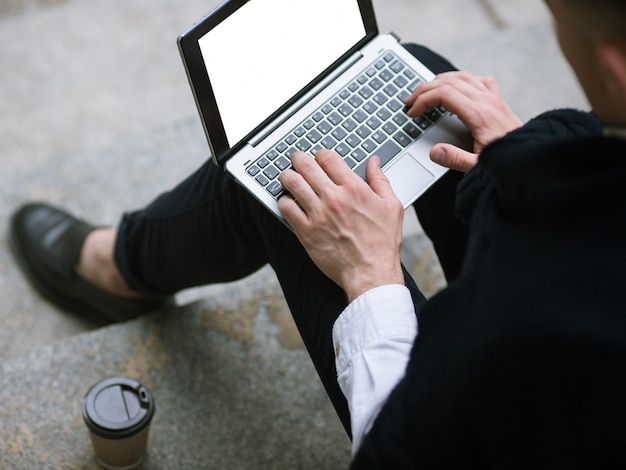 Communication sur les réseaux sociaux. Technologie pour les hommes. Travail à distance, homme d'affaires méconnaissable discutant en plein air vue de dessus, ordinateur portable avec maquette d'écran blanc vide