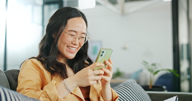 Communication téléphonique parlant et femme asiatique à la maison sur un canapé avec une conversation en ligne Appel téléphonique parlant et réseautant d'une personne sur un téléphone portable dans une maison de salon sur un canapé