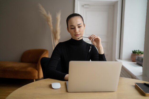 La communication vidéo en ligne d'une femme indépendante utilise un ordinateur portable au bureau