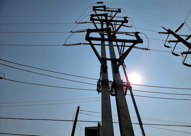 Commutateur de coupure de charge de 115 kV en position fermée sur un ciel bleu avec le fond brillant du soleil