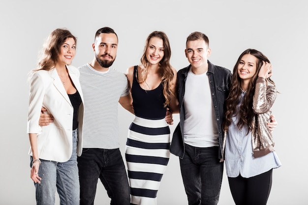 Compagnie d'amis dans des vêtements décontractés à la mode se tiennent ensemble et sourient sur un fond blanc dans le studio.