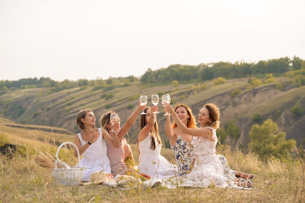 compagnie d'amis féminins bénéficie d'un pique-nique d'été et lever des verres avec du vin