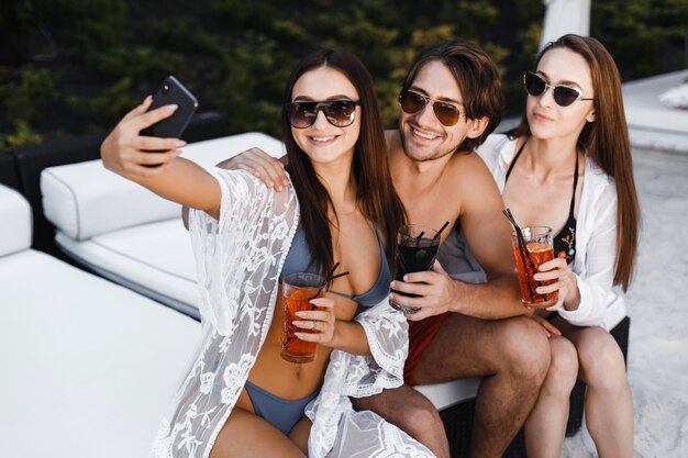 Compagnie d'amis prenant des selfies sur la plage