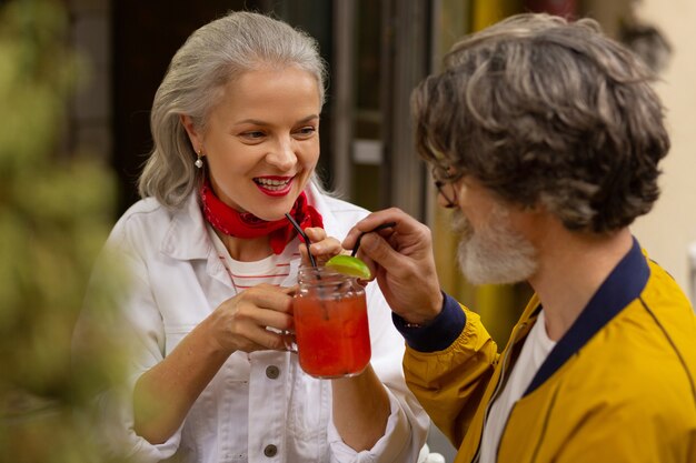 En compagnie d'un être cher. Heureux couple marié passant leur temps assis ensemble dans le café et buvant un smoothie.