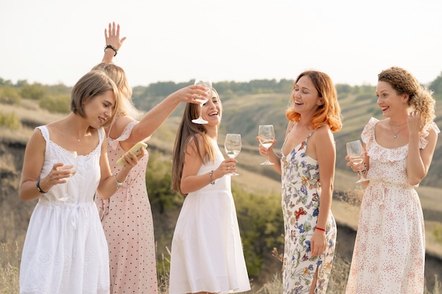 Photo la compagnie de magnifiques amies s'amuse et profite d'un pique-nique d'été vert, de la danse et de boire de l'alcool. concept de personnes.