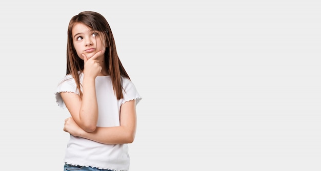 Photo complet du corps petite fille réfléchissant et levant les yeux