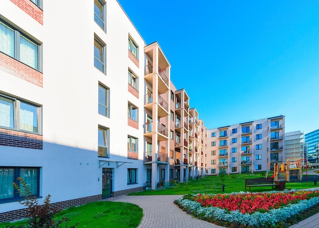 Complexe d'immeubles résidentiels modernes avec aire de jeux pour enfants et pot de fleurs comme installations extérieures.