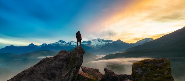 Photo composé d'aventure épique d'un homme randonneur au sommet d'une montagne rocheuse