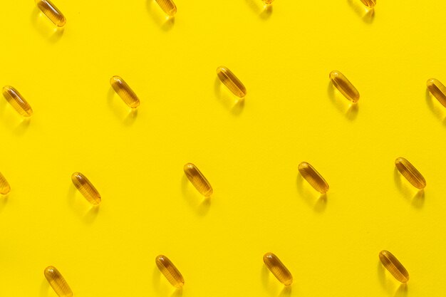 Composition abstraite avec des capsules d'huile de foie de morue sur fond jaune.