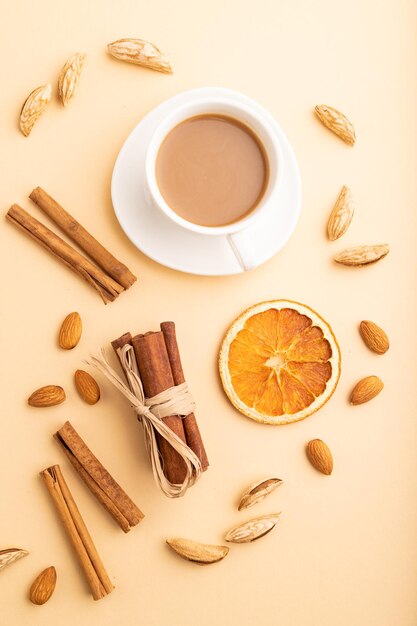 Composition avec amandes cannelle et tasse de café sur fond pastel orange vue de dessus gros plan