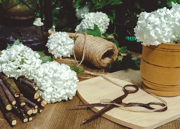 Composition d'antiquités sur une table en bois et bourgeons sphériques coupés de viorne Boulle de Neige aux nombreux pétales blancs.