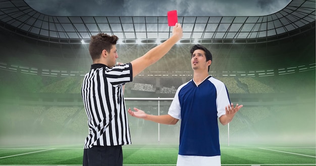 Photo composition d'un arbitre masculin tenant une carte rouge et un joueur au stade de football