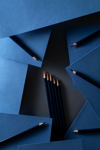 Composition d'art avec des crayons de couleur et des feuilles de papier indigo posées sur la table dans la clé sombre