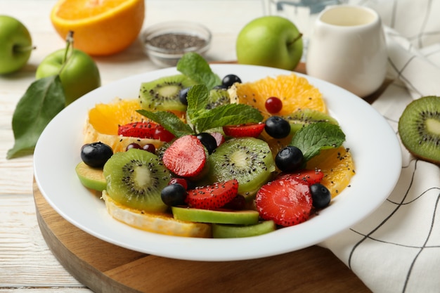 Composition avec assiette de salade de fruits frais sur table en bois