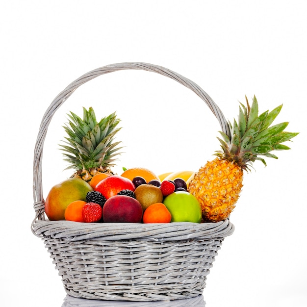 Photo composition avec un assortiment de fruits dans un panier en osier sur fond blanc