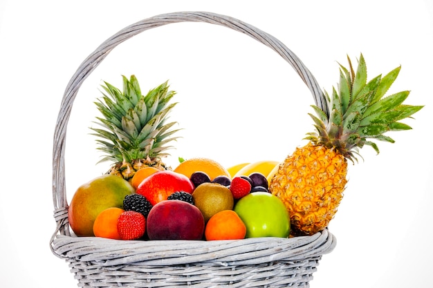 Photo composition avec un assortiment de fruits dans un panier en osier isolé sur blanc