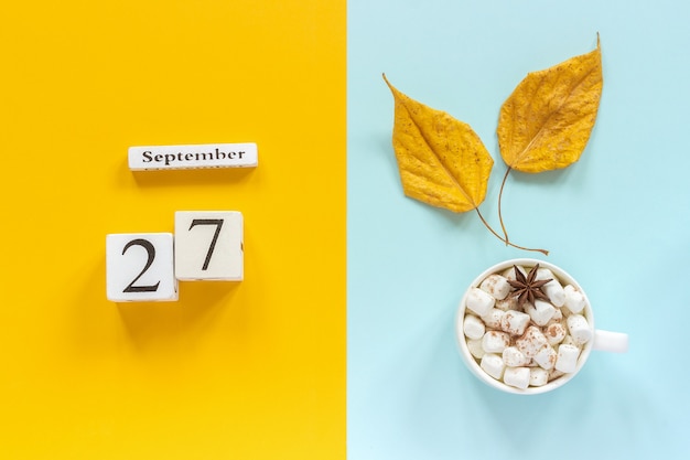 Composition D'automne. Calendrier En Bois 27 Septembre, Tasse De Cacao Avec Des Guimauves Et Des Feuilles D'automne Jaunes Sur Fond Bleu Jaune. Vue De Dessus Concept De Maquette à Plat Bonjour Septembre.