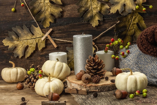 Composition d'automne avec décor traditionnel. Citrouilles blanches, bougies, feuilles d'automne, glands, cônes. Fond de planches de bois, espace de copie