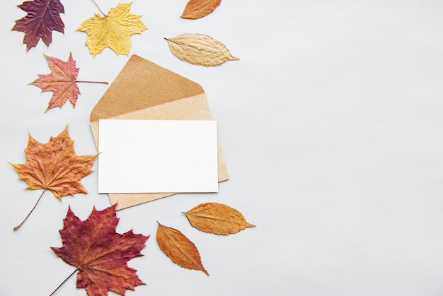 Photo composition d'automne avec des feuilles, enveloppe et carte vierge sur fond blanc